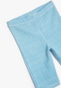 Ljusblå rutiga leggings tillverkade av ett mjukt, stretcht tyg. De har en åtsittande design med en smal midjeresår och en jämn yta.
