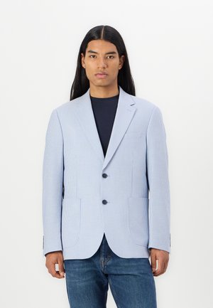 Svetlomodrý pruhovaný blazer s klopami, dvoma prednými vreckami a dvoma čiernymi gombíkmi. Nosený cez námornícky tričko, v kombinácii s džínsy.