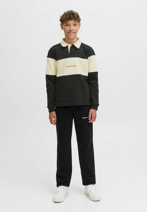 Svart och krämfärgad färgblockerad långärmad polo skjorta med krage, kombinerad med svarta sweatpants. Har broderi framtill och vita sneakers.