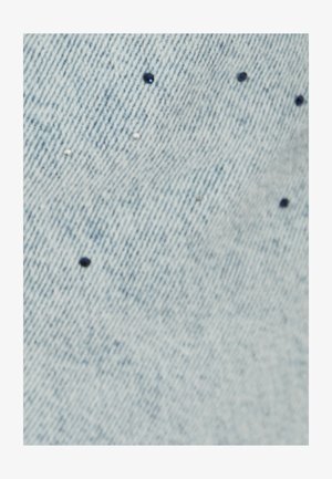 Hellblauer Denim-Stoff mit verstreuten kleinen schwarz-weißen Verzierungen auf der Oberfläche, die Textur und visuelles Interesse hinzufügen.