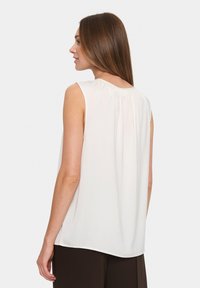 Blusa bianca senza maniche con scollo arricciato, tessuto leggero, morbido al tatto e dal fit rilassato; la vista dal retro mostra un orlo leggermente curvo.