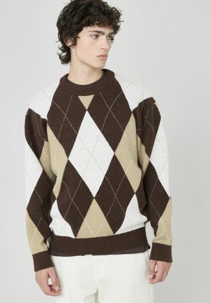 Pull en argyle marron, crème et beige avec un col rond, tricot texturé et poignets côtelés, présentant des formes de losanges diagonales.
