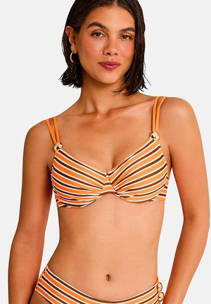 Vrouw draagt een bikinitop met oranje, witte en bruine strepen, dubbele schouderbandjes en gouden knoopaccenten.