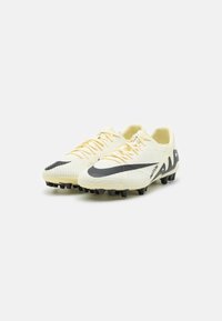 Botines de fútbol amarillo claro con un swoosh negro, parte superior texturizada y tacos negros. Presentan un diseño aerodinámico y cierre de cordones.