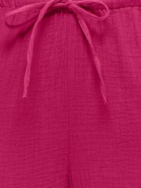 Gros plan sur un tissu rose vif avec un cordon noué à la taille et un motif texturé subtil.