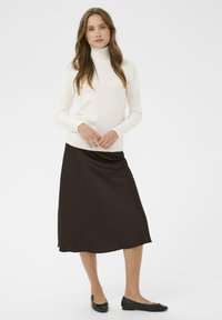 Suéter crema de cuello alto y falda midi marrón oscuro, textura suave, cintura ajustada, bailarinas negras, diseño minimalista.