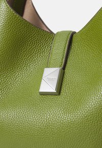 Bolsa de mão em pele verde com textura pebble, um detalhe em hardware prateado triangular e um design estruturado.