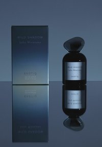 Czarna szklana butelka perfum z zaokrąglonym, kamiennym korkiem. Pudełko posiada gradient od ciemnoniebieskiego do jasnoniebieskiego, z srebrnym tekstem. Powierzchnia odblaskowa.