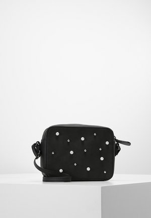 Bolso bandolera rectangular negro con una correa desmontable, decorado con tachuelas dispersas de perlas blancas y plateadas en la parte frontal.