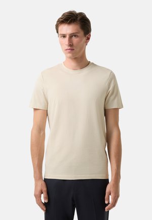 Cream-colored cotton t-shirt with a crew neck and short sleeves. Features subtle embossed logo on the chest. Smooth texture, relaxed fit.