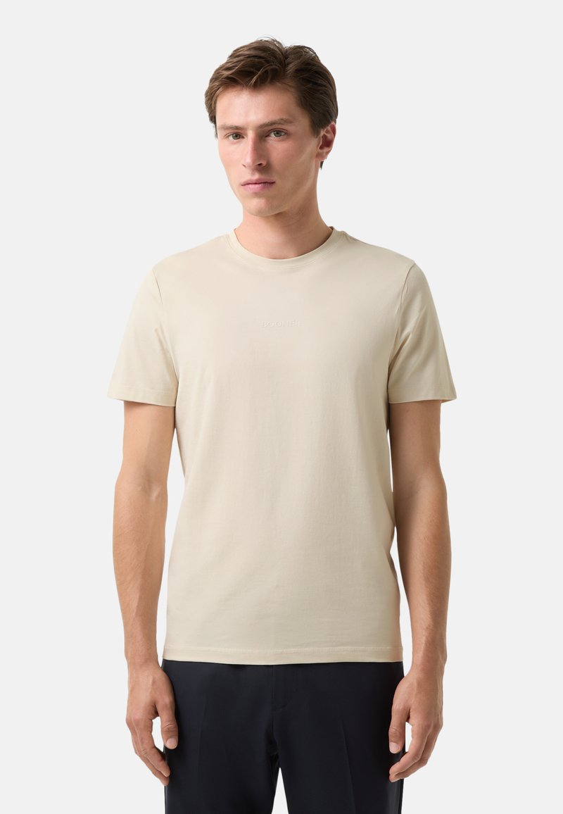 Cremefarvet bomulds t-shirt med rund hals og korte ærmer. Har et diskret præget logo på brystet. Glat tekstur, afslappet pasform.