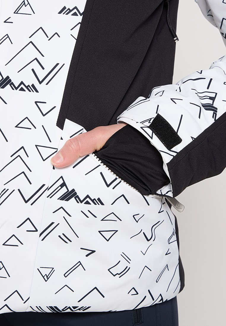 Czarna i biała kurtka w wzory z kątowymi wzorami, z kieszenią na zamek i czarnymi mankietami. Wykonana z lekkiego materiału o gładkiej teksturze.