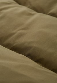 Jasnozielona pikowana tkanina o gładkiej strukturze i puszystym wykończeniu, z miękkimi, zaokrąglonymi konturami i subtelnym połyskiem.