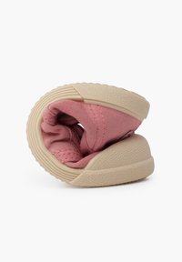Scarpa in tessuto rosa con forma tondeggiante, dotata di una suola in gomma beige testurizzata e un aspetto morbido e stropicciato.