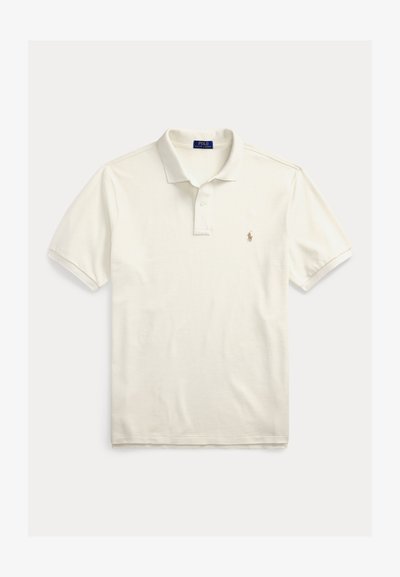 Trumpomis rankovėmis siūtas polo marškinėlis iš kreminės spalvos medvilnės. Turi klasikinius apykaklę, dviejų mygtukų skylių eilutę ir mažą siuvinėtą logotipą kairiajame krūtinės srityje.