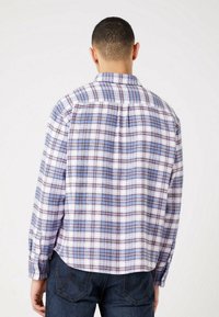 Geruite fleeceblouse met paarse, blauwe en witte kleuren; heeft een knoopsluiting kraag en lange mouwen; losse pasvorm met een afgeronde zoom.