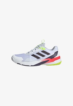 Zapatilla deportiva con parte superior de malla blanca, rayas negras y detalles en verde neón. Incluye una suela multicolor con detalles en rojo y rosa.