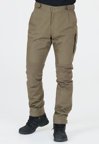 Pantalons de plein air kaki en tissu durable et texturé ; dotés de panneaux de genoux renforcés et d'une poche zippée sur le côté. Accompagnés de bottes de randonnée noires.