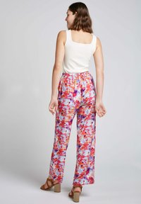 Pantalons fleuris multicolores avec une taille élastique, coupe ample et tissu léger. Le design présente des teintes de rose, violet et orange.