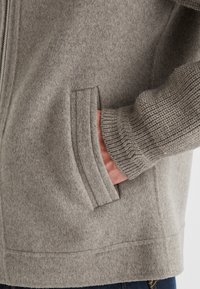 Graue Fleecejacke mit Reißverschluss, Seitentaschen, gerippten Bündchen und einem strukturierten Stoff für Wärme und Komfort. Mit einem glatten Finish kombiniert.