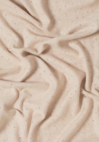 Tissu beige avec une texture douce, parsemé de paillettes dorées créant un motif de points subtils sur toute la surface.