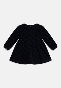 Schwarzes Cordkleid mit langen Ärmeln, Sternenmuster und ausgestelltem Rock. Enthält einen Reißverschluss auf der Rückseite und geknöpfte Manschetten.