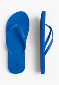 Tongs en caoutchouc bleu avec des semelles plates, des brides en forme de V et un semelle intérieure texturée. Présente un logo de skull et os croisés sur la semelle.