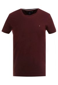 Burgundy bomull t-shirt med rund hals, korta ärmar och en liten logotyp-accent på vänster bröst. Slät textur och klassisk passform.
