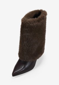 Bota de cuero marrón de punta afilada con un suave puño de piel sintética marrón. Diseño elegante con una textura lisa y brillante y una silueta de tobillo ajustada.