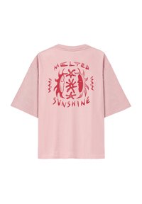 Różowa bawełniana koszulka oversized z czerwoną grafiką na plecach, na której widnieją słowa "ROZTOPIONE SŁOŃCE" oraz abstrakcyjne wzory.