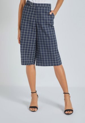 Culottes navy con un patrón de cuadros blancos, con una cintura ajustada, bolsillos laterales y un corte relajado que cae por debajo de la rodilla.