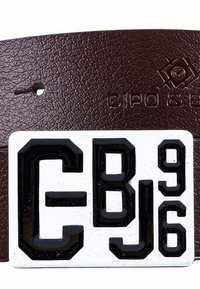 Bruine leren riem met textuur, voorzien van een rechthoekige witte plaat met verhoogde zwarte letters en cijfers: "CBJ96".