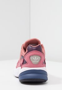 Scarpa sportiva rosa e viola con una parte superiore in tessuto testurizzato, tallone imbottito, intersuola bianca e suola in gomma. Presenta il logo adidas sul tallone.