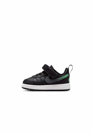 Zapatilla negra para niño pequeño con suela blanca, cierre de velcro y logo gris oscuro, con un detalle verde en la lengüeta del talón y la parte trasera.