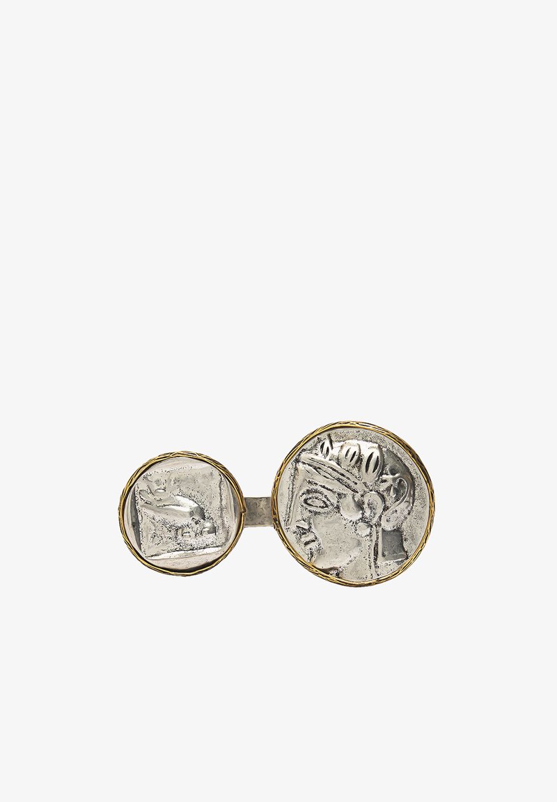 Srebrny podwójny broszka w kształcie monety z misternymi detalami; zawiera większą, okrągłą monetę z profilem oraz mniejszą, kwadratową monetę przedstawiającą dłoń. Złote akcenty.