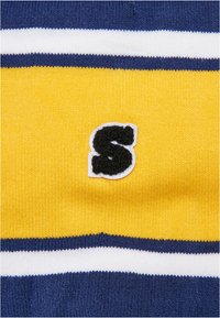 Material tricotat de culoare galbenă cu dungi bleumarin și alb; are o aplicație texturată cu litera "S" de culoare neagră; textură netedă în ansamblu.