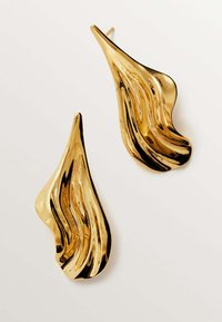 Pendientes de metal dorado con un diseño en forma de onda, que presentan una superficie pulida y reflectante y una forma escultórica alargada.