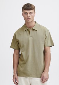 Oliven grønn polo skjorte med klassisk krage og korte ermer, med en placket og glatt, teksturert stoff.