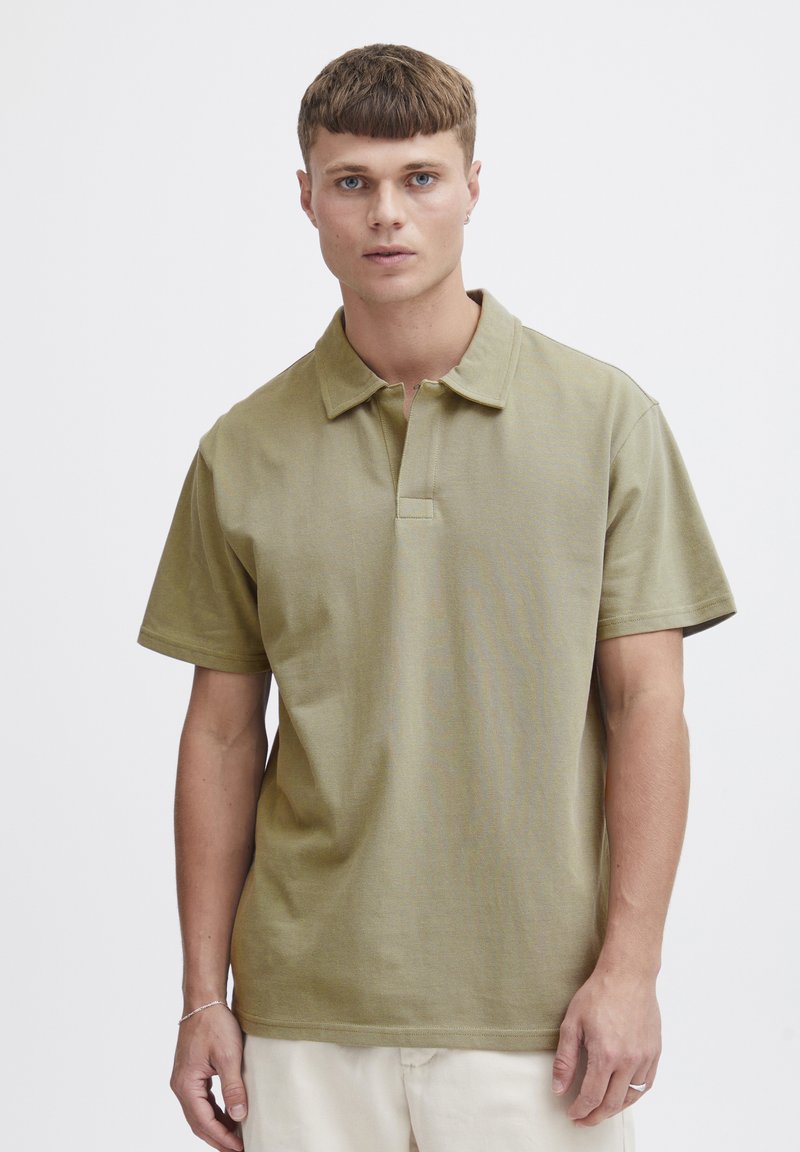 Oliven grønn polo skjorte med klassisk krage og korte ermer, med en placket og glatt, teksturert stoff.