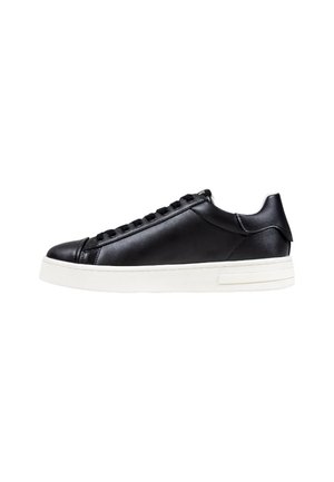 Sneaker nera a vita bassa in pelle con lacci neri e suola spessa in gomma bianca, vista laterale su sfondo bianco.