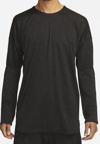 Zwarte langemouwen T-shirt met een gestructureerd, ribbelpatroon. Heeft een ronde halslijn en een relaxed fit met raglanmouwen en een afgeronde zoom.