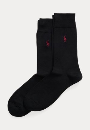 Paire de chaussettes noires montantes avec logo joueur de polo brodé en rouge sur le côté, affichées à plat sur fond blanc.