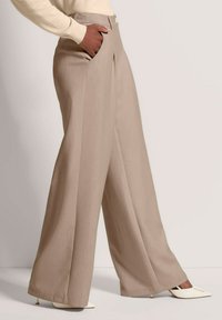 Beige broek met brede pijpen en een gladde textuur, voorzien van een voorplooi, zijzakken en een enkele knoopsluiting in de taille.