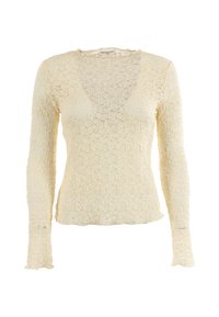 Top in pizzo crema a maniche lunghe con scollatura a V e bordi leggermente ondulati, caratterizzato da un motivo floreale in pizzo e una silhouette aderente.