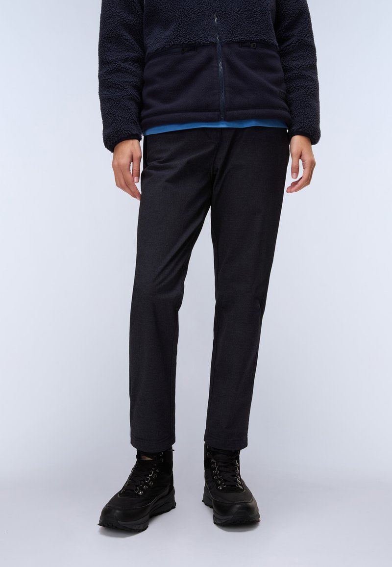 Schwarze, gerade geschnittene Hose aus strapazierfähigem Material, kombiniert mit einer marineblauen Fleecejacke und schwarzen Wanderstiefeln. Einfaches, funktionales Design.