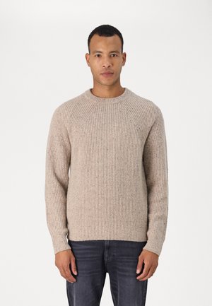 Beiger Strickpullover mit Rundhalsausschnitt und gerippter Textur. Verfügt über Raglanärmel und einen geraden Saum. Getragen mit dunklen Jeans.