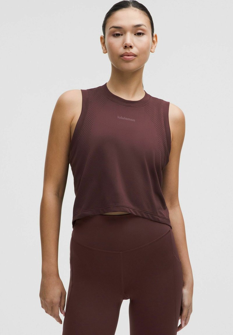 Bordo sportinis marškinėlis be rankovių, tekstūruota medžiaga ir logotipo detalė kaklo srityje, derinamas su atitinkamomis legging'ų kelnėmis.