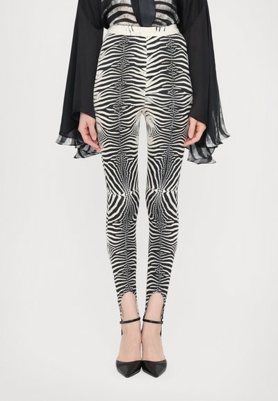 Sort-hvide zebraprinte leggings med høj talje, der har en glat tekstur og ankeludskæringer. Sættet er parret med sorte spidse hæle.