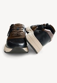 Sneaker neri e marroni con tomaia in suede testurizzato e pelle liscia. Le caratteristiche includono una chiusura con zip e una suola chunky beige a contrasto.