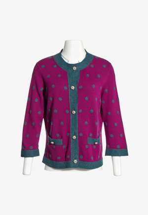 Cardigan violet à pois bleus, bordure bleue, boutons argentés, deux poches avant et manches trois-quarts sur un mannequin blanc.